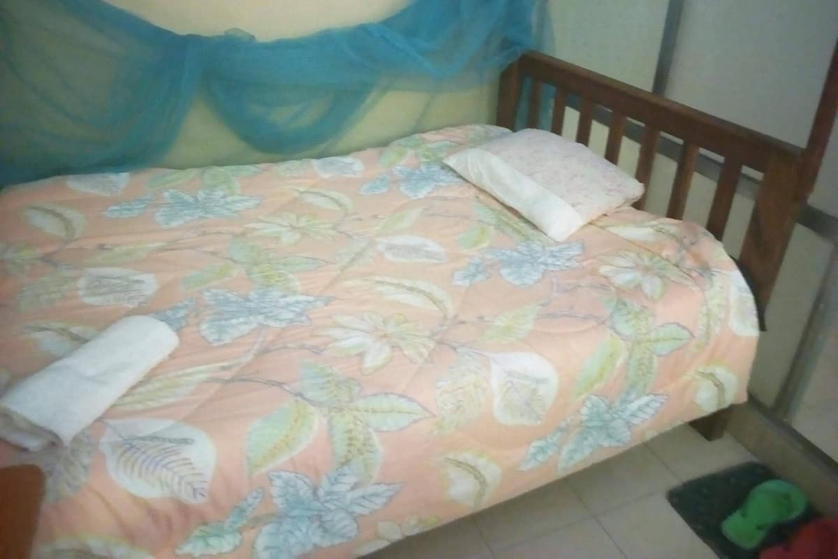 Un lit avec une couvre-lit à motifs floraux, une tête de lit en bois et un rideau bleu.
