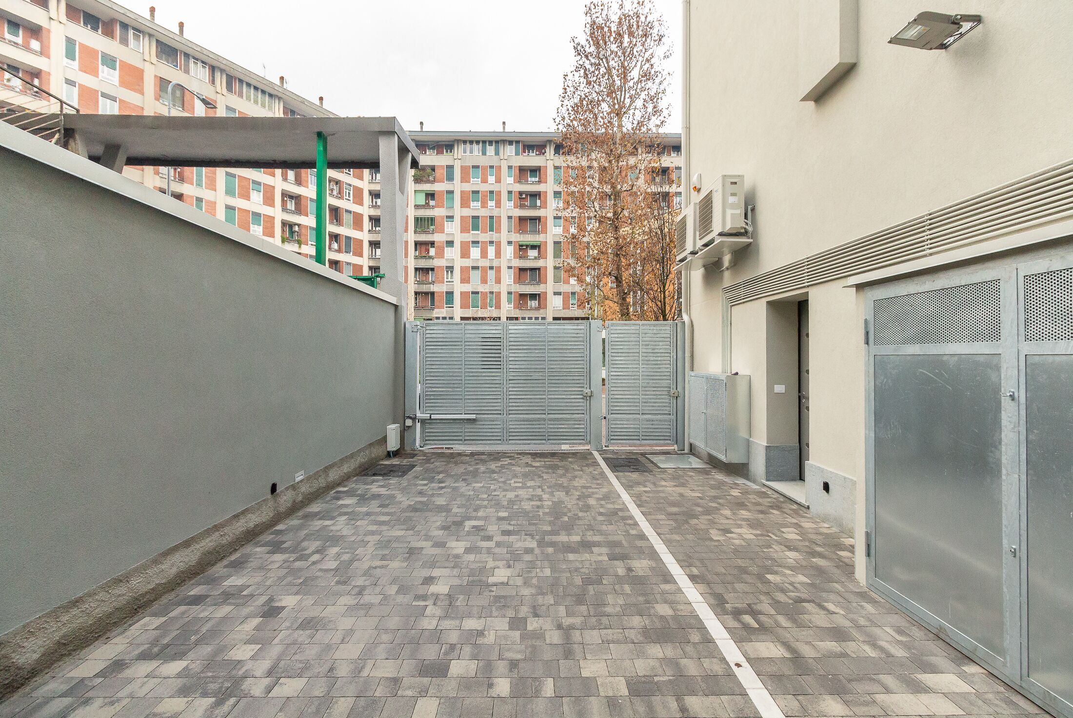 Ein Innenhof mit Fliesenboden, einem Metallgitter und einem Gebäude im Hintergrund.