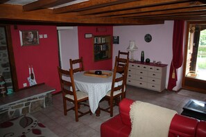 Un comedor con una mesa y sillas, una estantería y un sofá rojo.