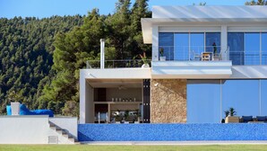 Una casa moderna a due piani con un balcone, un muro in pietra e una zona con piastrelle blu.
