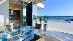 Zona pranzo con tavolo apparecchiato per due, con vista sulla piscina e sul mare.