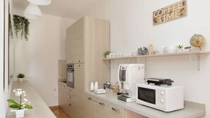 A modern kitchen with a microwave, coffee machine, and a shelf with coffee cups and a globe. - B&B Felicioni (Fiumicino)