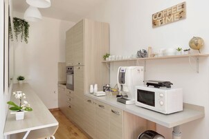 Egy modern konyha, amelyben mikrohullámú sütő, kávéfőző található, valamint egy polcon kávéscsészék és egy földgömb áll.