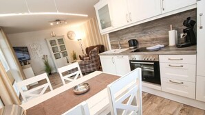 Eine moderne Küche mit weißen Schränken, einer Holz Arbeitsplatte und einem Essbereich mit weißen Stühlen und einem Tisch.