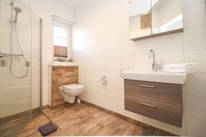 A modern bathroom with a shower, toilet, and vanity.