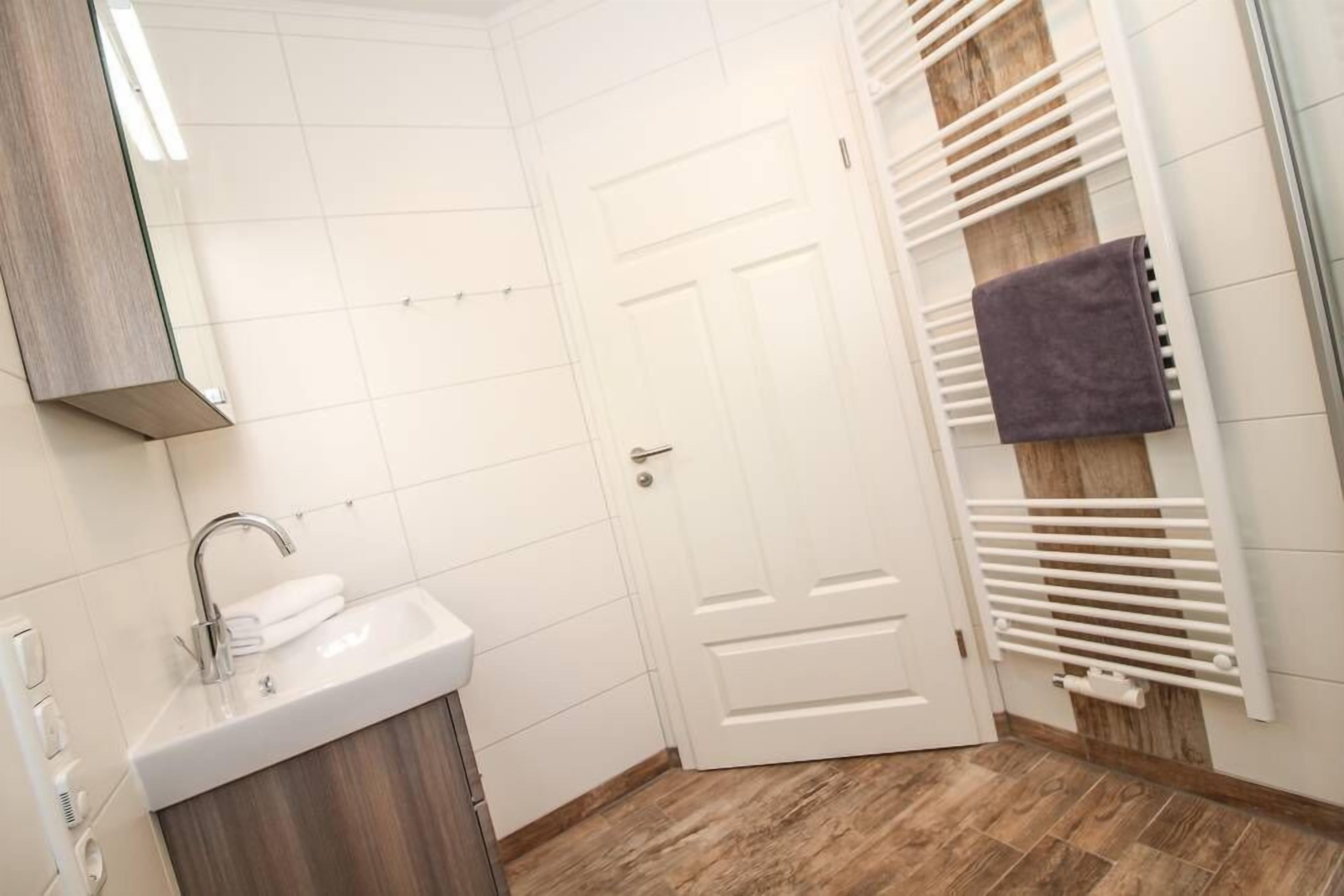 A bathroom with a white sink, a mirror, and a towel rack.