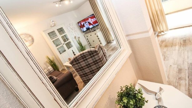 Ein modernes Wohnzimmer mit Fernseher, Sofa und Dekorationselementen.