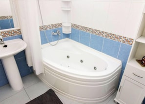 Un bagno con una vasca da bagno bianca, un lavandino e un armadietto.