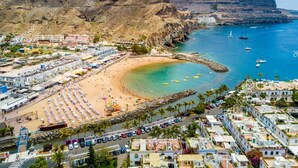 A coastal town with a beach, boats, and a rocky cliff. - Playa Azul , Luxury Penthouse With Spectacular Roof Terrace (Mogan)