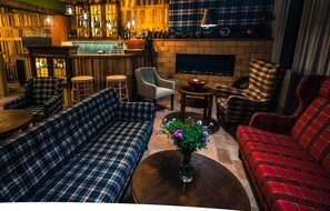 A bar area with seating, a fireplace, and a bar counter.