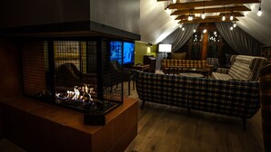 Una sala de estar acogedora con chimenea, un sofá a cuadros y un televisor.