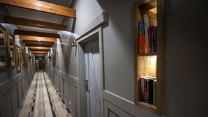 Un pasillo con vigas de madera, una puerta con la etiqueta '1-3' y una estantería llena de libros.