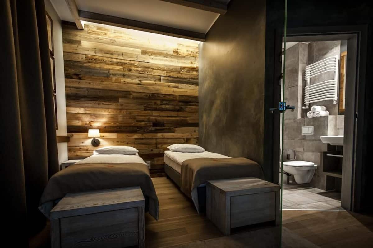 Een kamer met twee bedden, een houten wand, een badkamer met badkuip en een modern design.