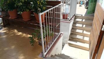 A staircase with a metal railing, potted plants, and a wooden bench.