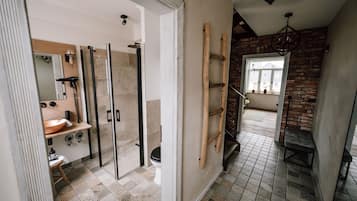 Ein modernes Badezimmer mit Duschkabine aus Glas, einem Holzboden und einer sichtbaren Toilette.