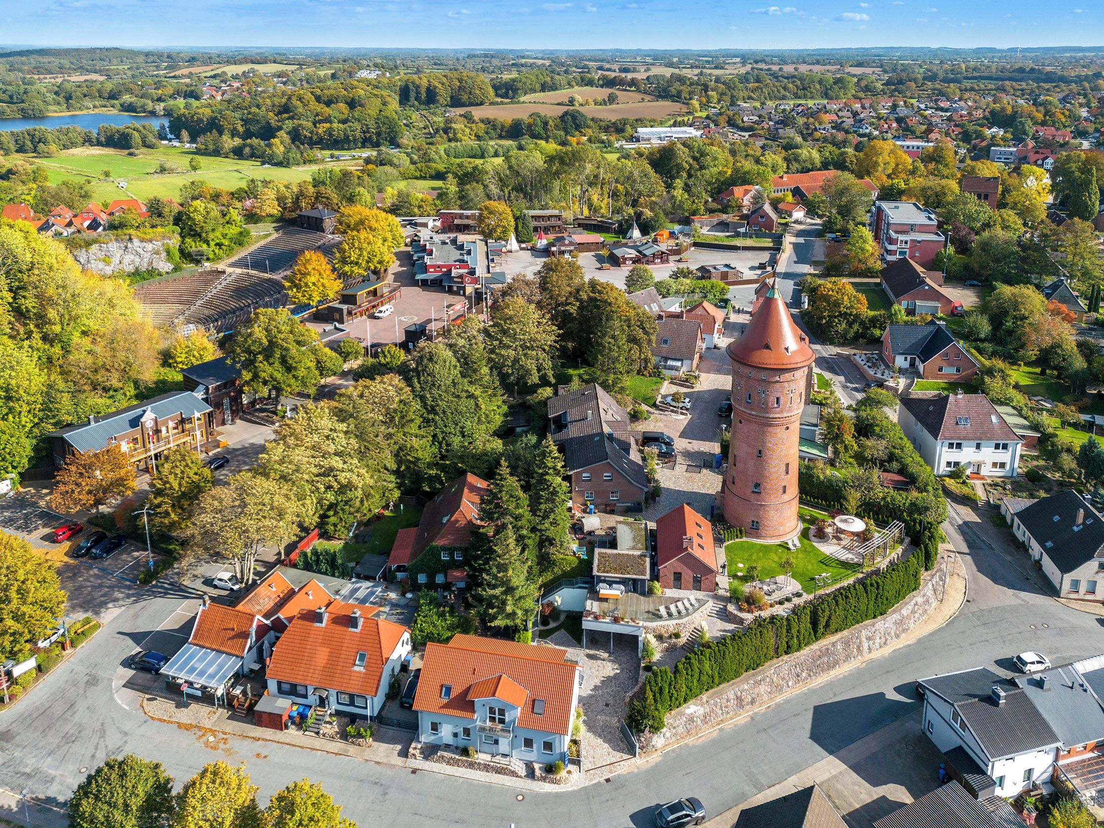 A town with a prominent tower, surrounded by residential buildings and a large open field.