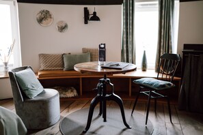 A cozy living room with a round wooden table, two chairs, a sofa, and a small dog. - Apart Hotel Wasserturm (Bad Segeberg)