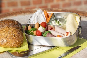 A meal with bread, vegetables, and meat in a metal container. - Apart Hotel Wasserturm (Bad Segeberg)