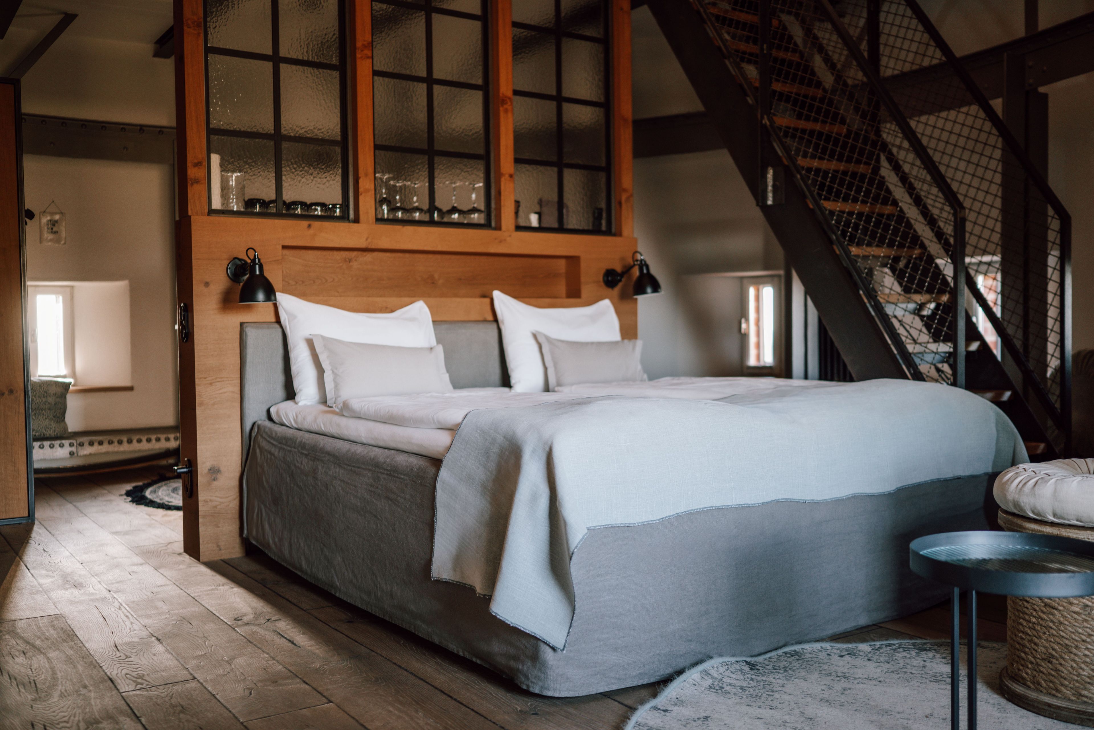 Ein Schlafzimmer mit einem großen Bett, einem Holzkopfstück und einer Treppe.