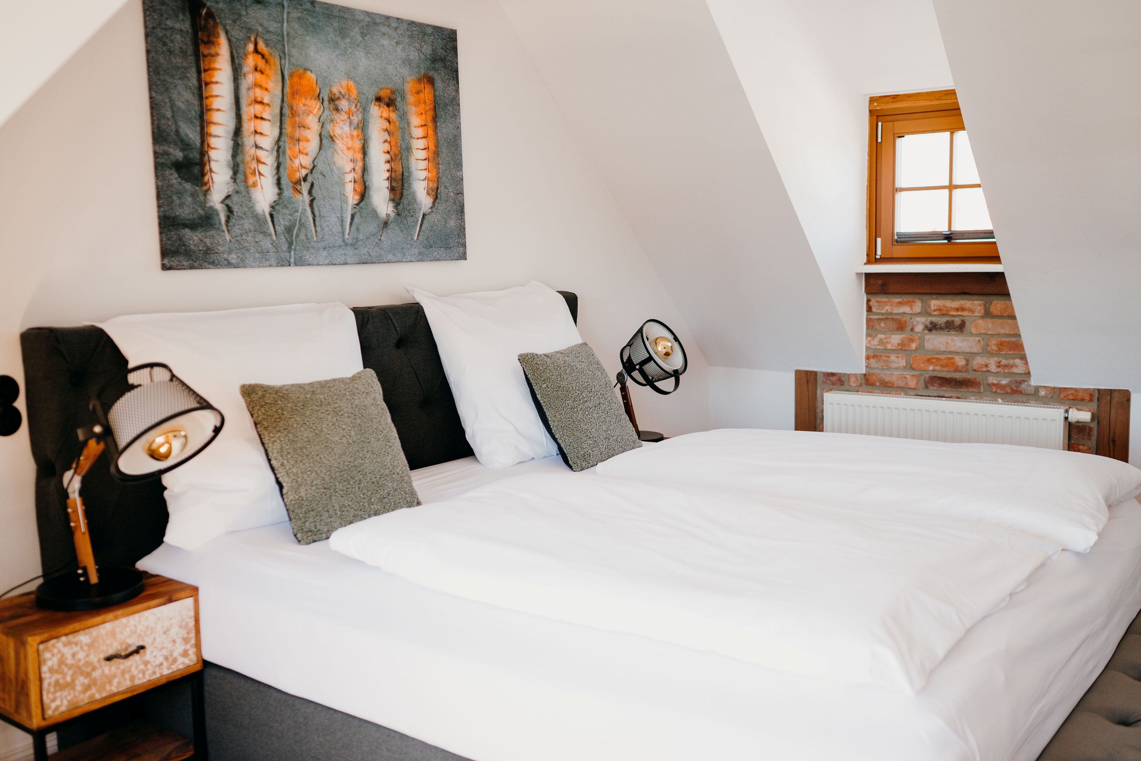Un dormitorio con una cama grande, una mesita de noche con lámpara, un cuadro en la pared y una chimenea de ladrillo.