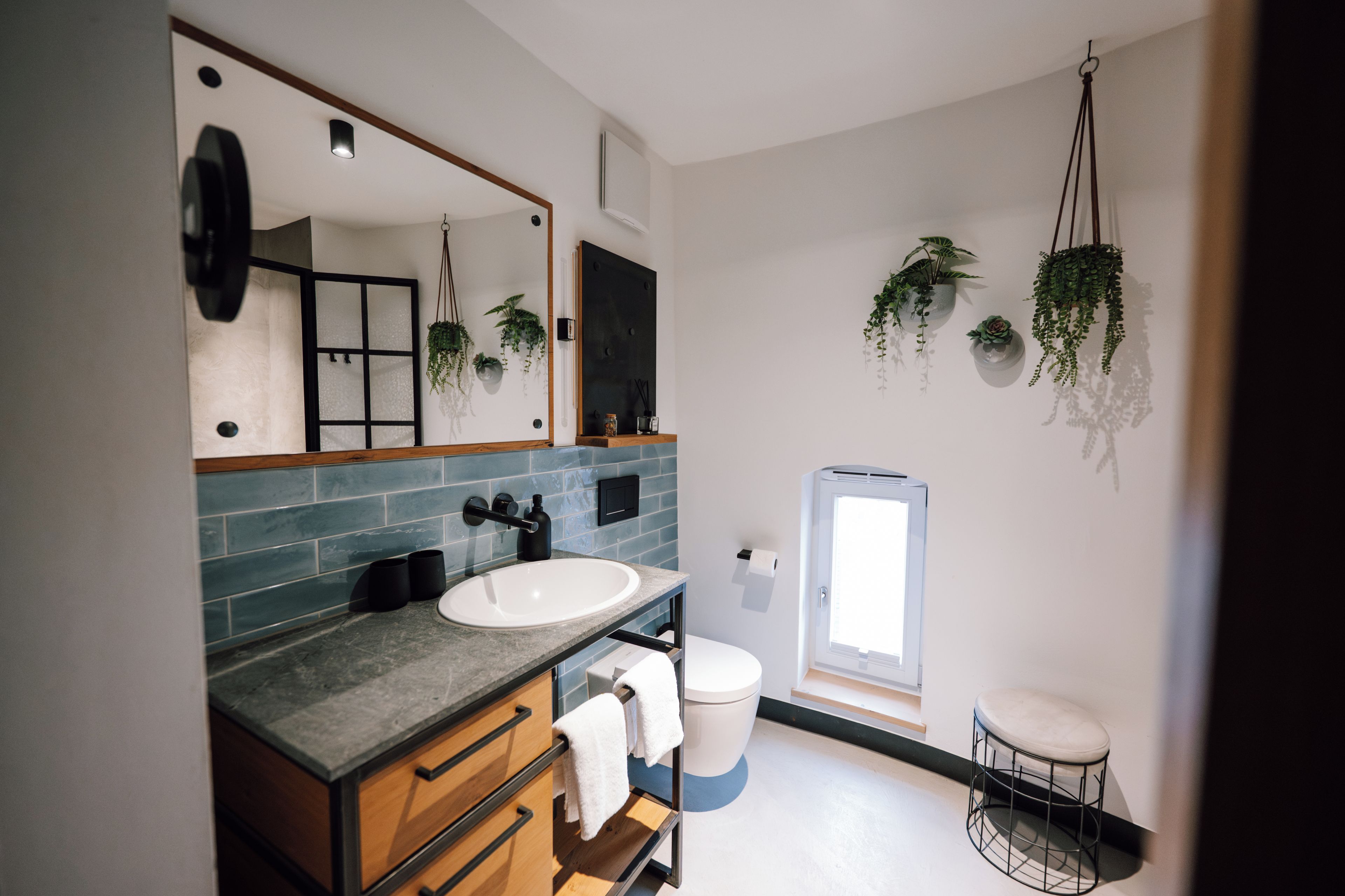 Un baño moderno con un espejo grande, un lavamanos, un inodoro y una ventana.