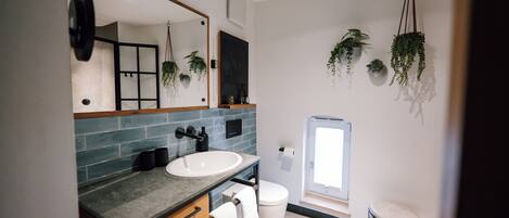 Un baño moderno con un espejo grande, un lavamanos, un inodoro y una ventana.
