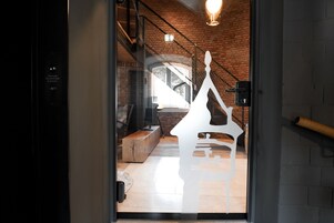 Un interior moderno con una escalera, un banco de madera y una puerta de vidrio con un corte en silueta.
