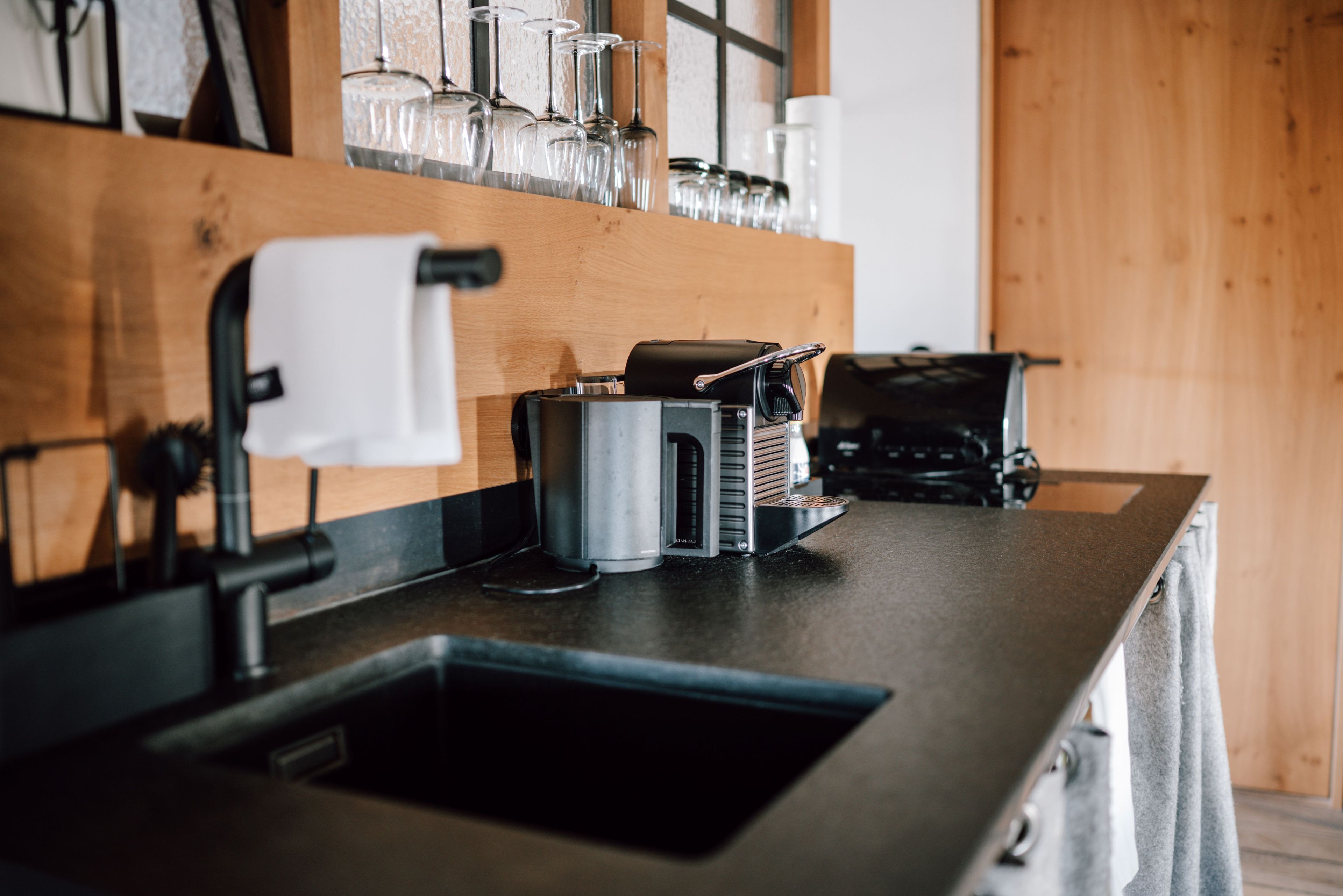 Una encimera de cocina con una cafetera, un lavabo y una ventana con vistas al exterior.