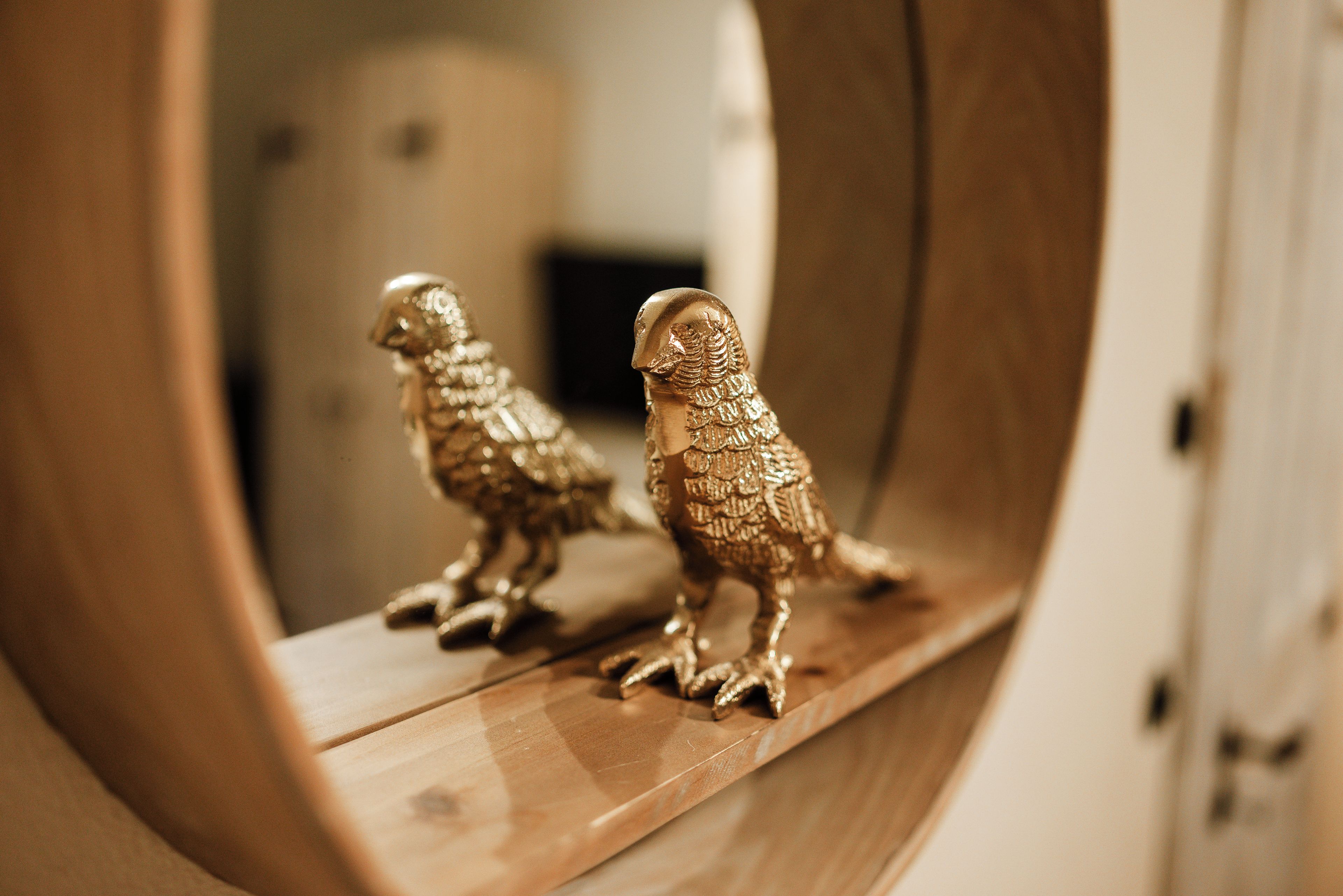 A wooden shelf with two golden owl figurines.