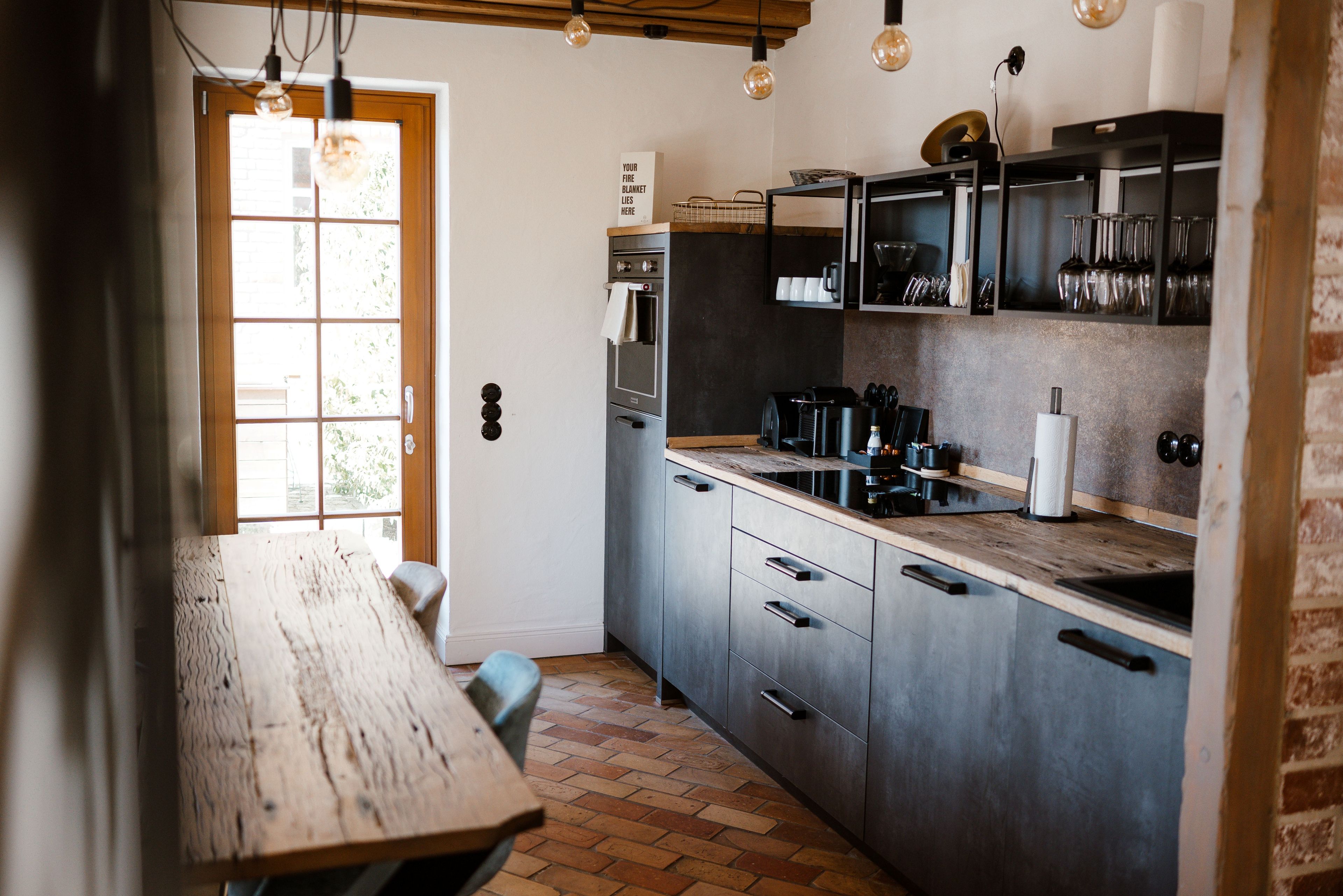 A compact kitchen with a wooden table, a built-in oven, and a coffee machine.