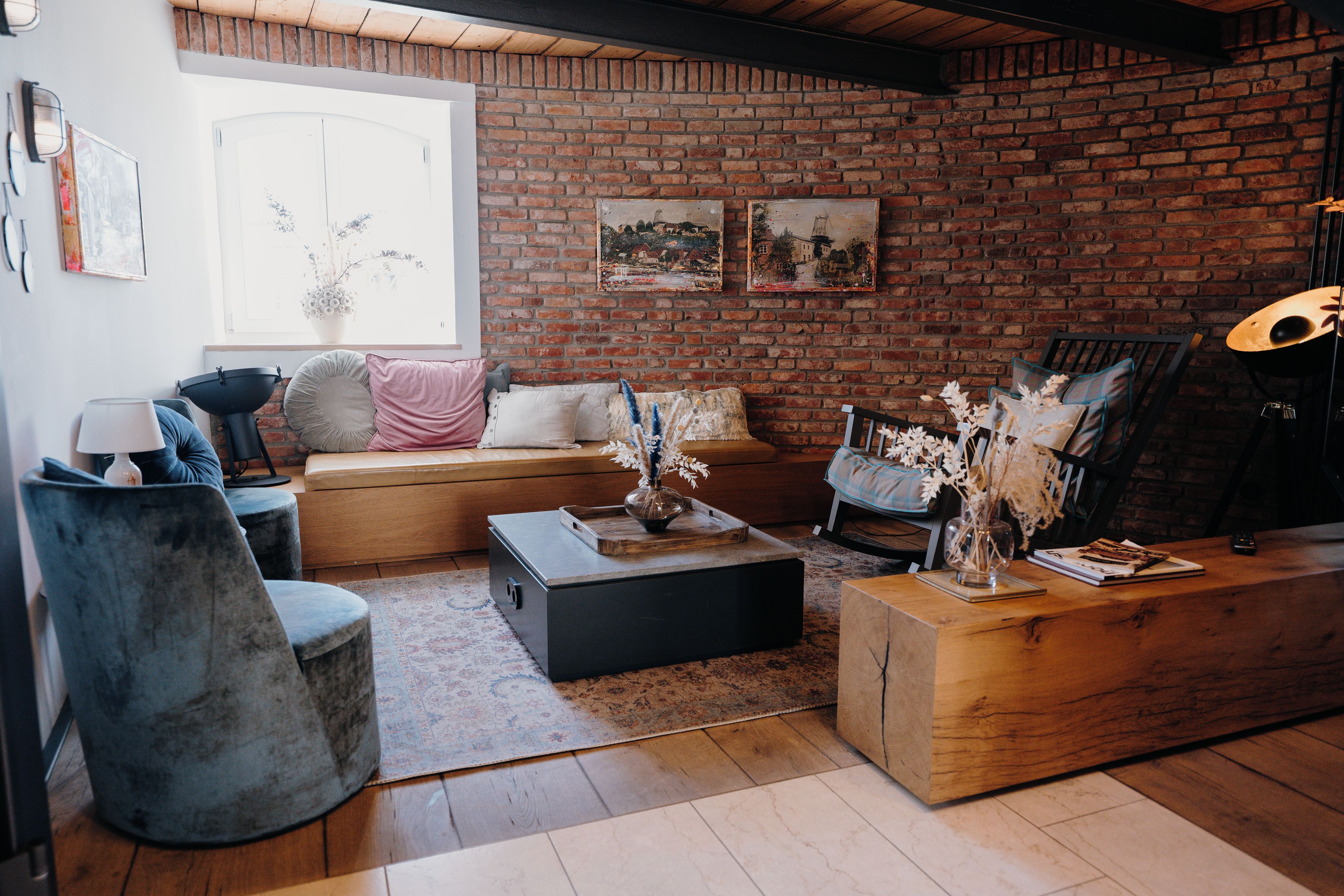 A cozy living room with a brick wall, a sofa, a coffee table, and a drum set.