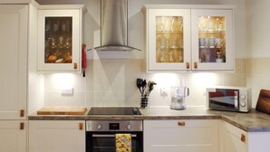 A kitchen with white cabinets, a stainless steel range hood, a microwave, and a coffee maker.