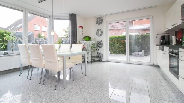 Cozinha moderna com área de jantar, janelas amplas e vista para o exterior.