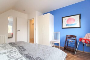 A bedroom with a bed, a wardrobe, a chair, and a table. - Rote & Grüne Mühle (Krummhoern)