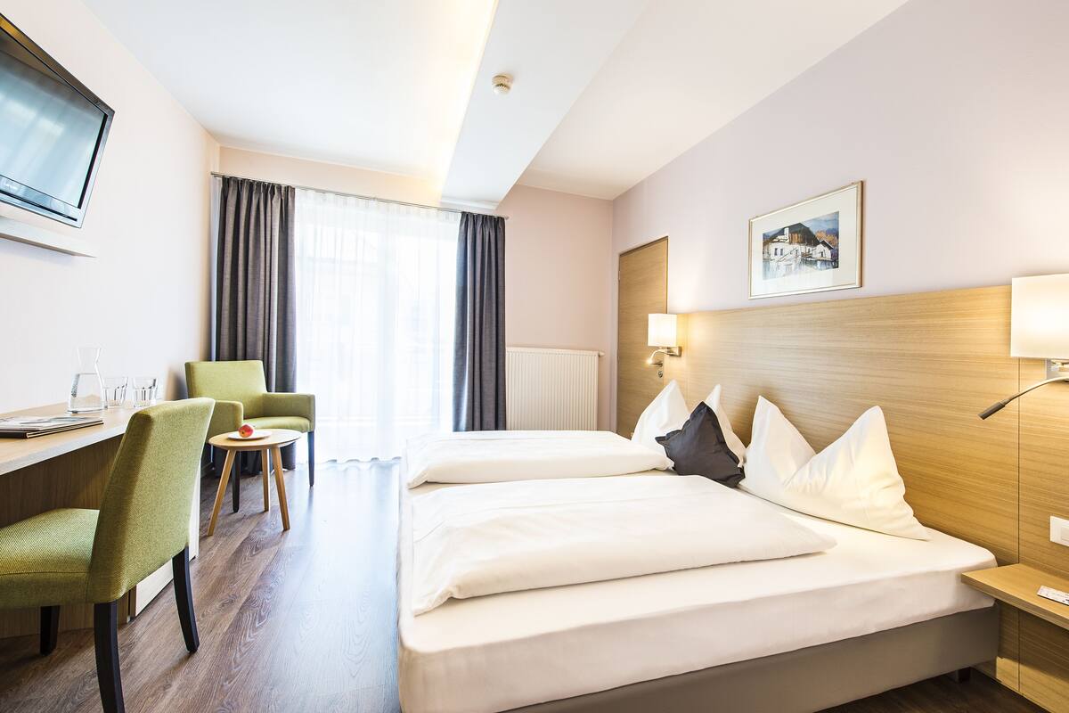 Ein Hotelzimmer mit Bett, Schreibtisch, Stuhl, Lampe und einem Bild an der Wand.