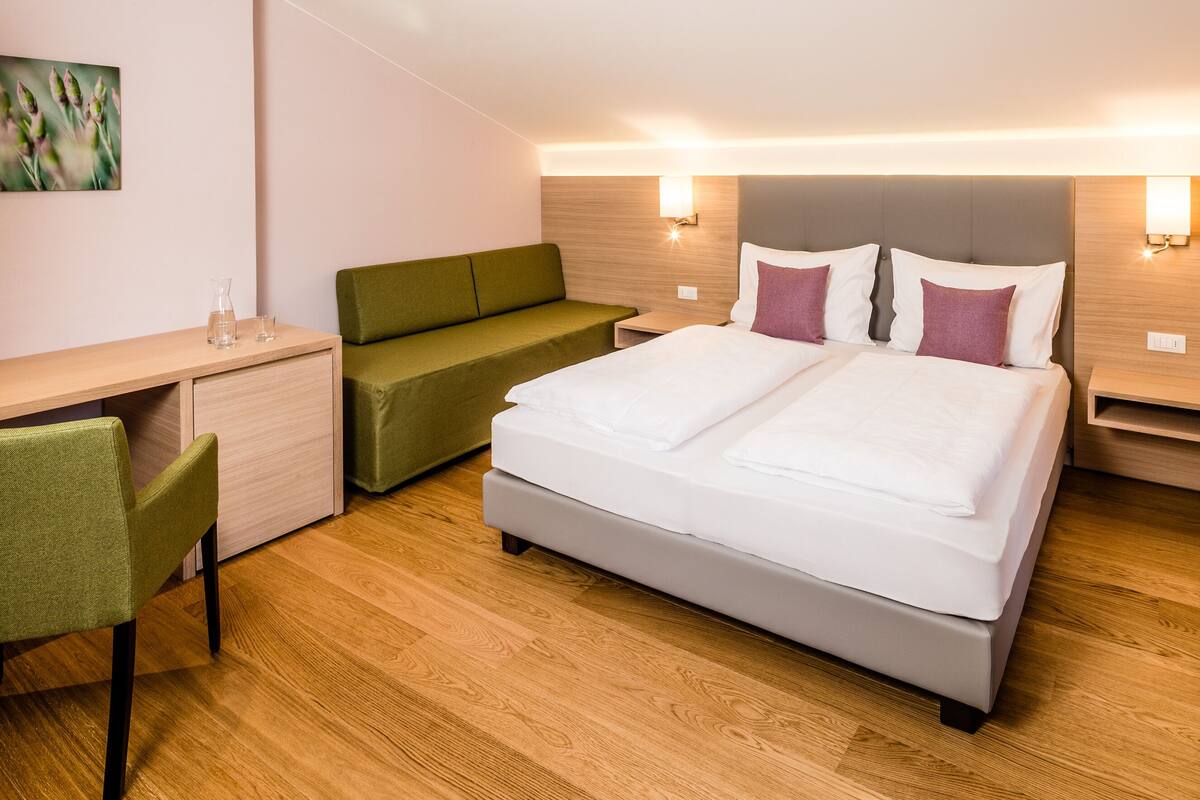 Ein modernes Hotelzimmer mit einem Bett, einem Schreibtisch, einem Stuhl und einer kleinen Couch.