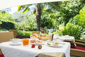 A breakfast table set outdoors with a variety of food items, including fruits, bread, and beverages. - Hotel Jardis (Lana)