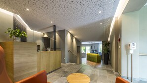 Ein moderner Empfangsbereich mit einem Holzbüro, orangenen Sitzgelegenheiten und einem gefliesten Boden.