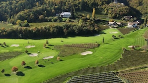 Ein Golfplatz mit mehreren Bunkern, einem Clubhaus und umliegenden Weinbergen.