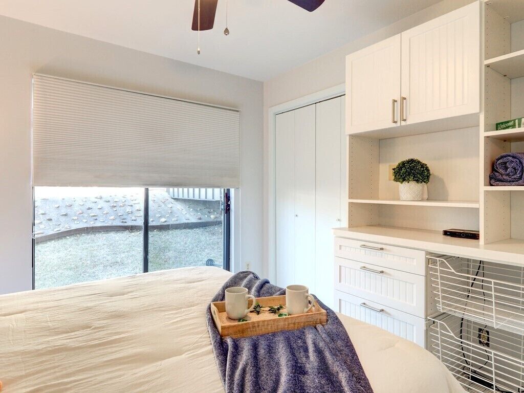 A bedroom with a bed, a tray with two mugs, a potted plant, and a wardrobe.