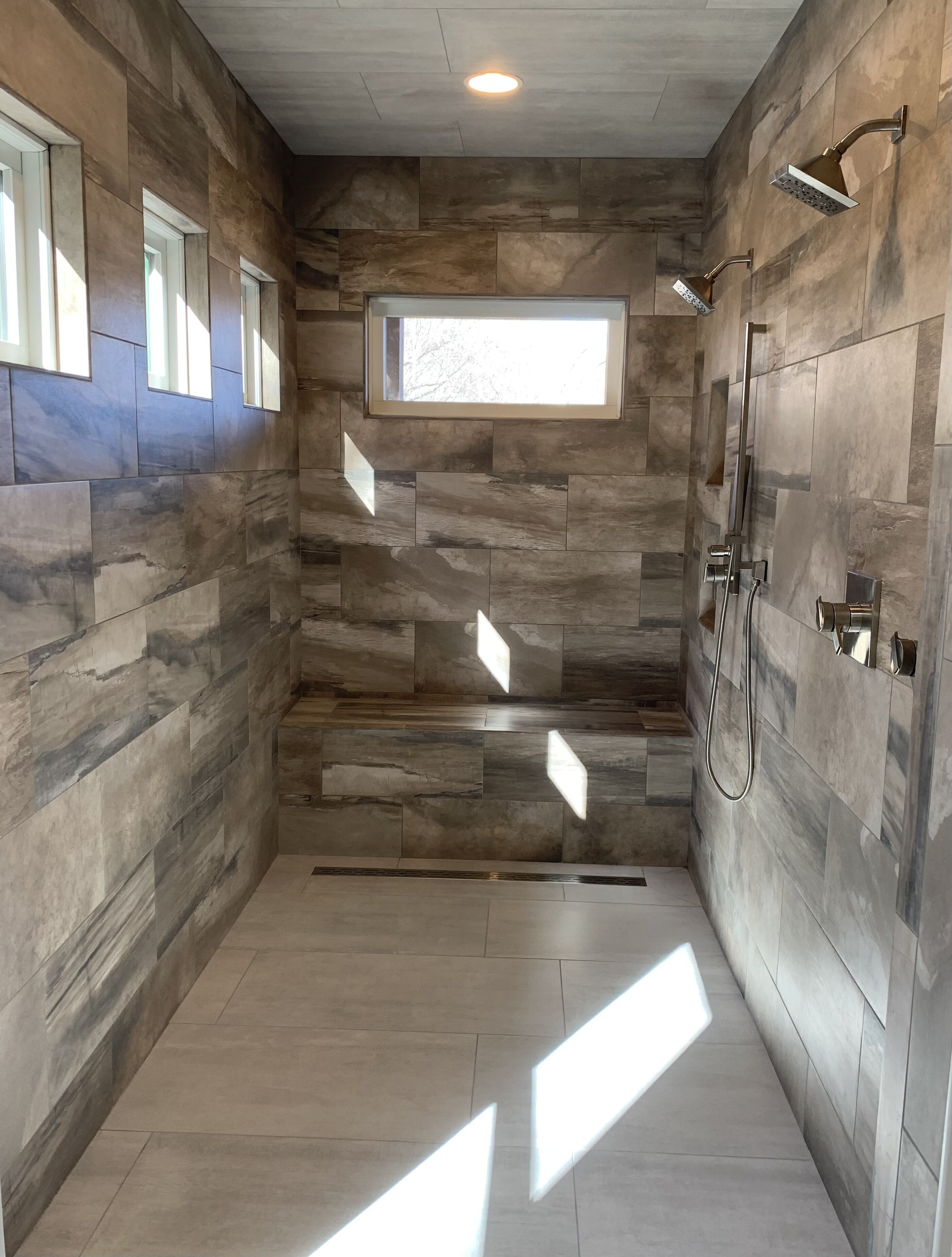 A modern shower area with a built-in window, a showerhead, and a hand shower.
