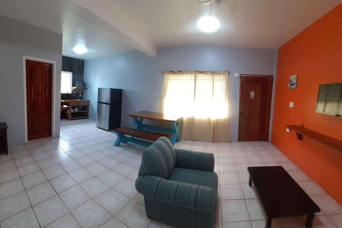 A living room with a sofa, a coffee table, and a TV mounted on the wall.