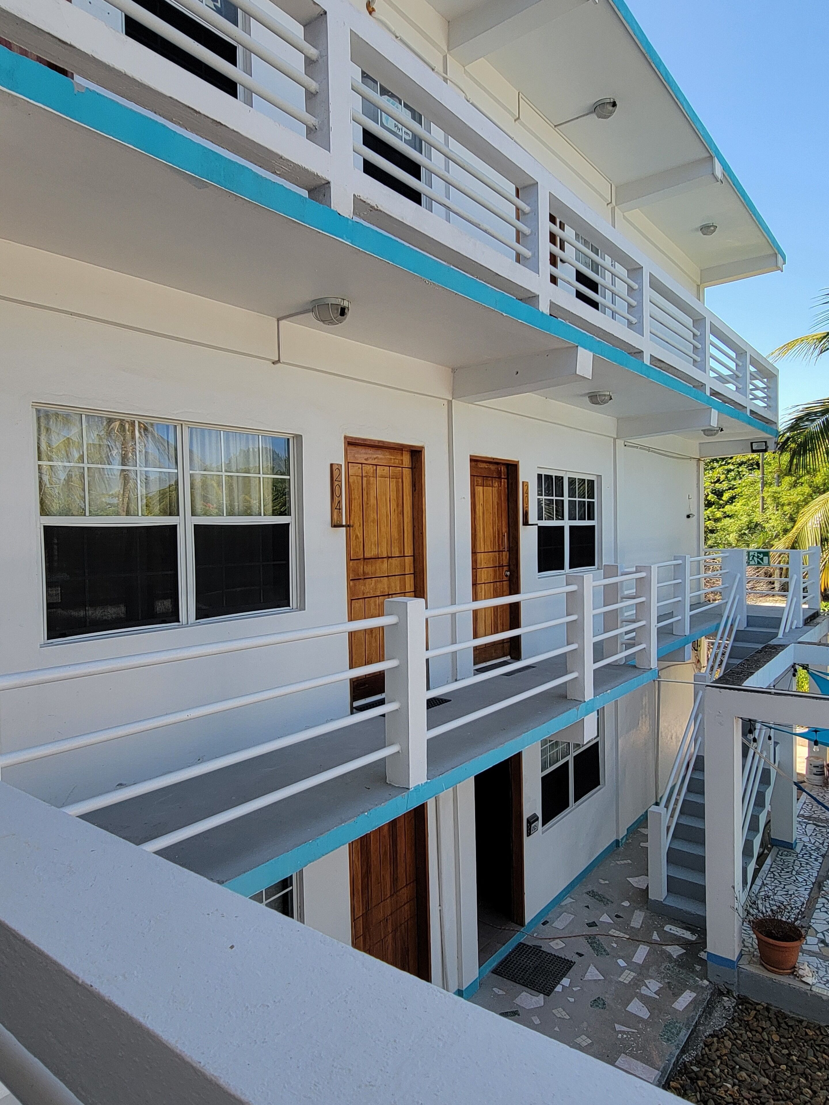 A multi-story building with balconies, wooden doors, and a tiled ground floor.