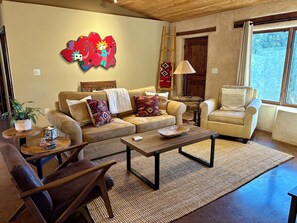 A living room with a sofa, armchair, coffee table, and a decorative wall piece. - Hiking, mt biking, 44 acres to explore, 20 min outside of Santa Fe (Santa Fe)