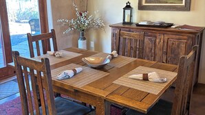 A dining area with a wooden table, chairs, a chandelier, a vase with branches, a framed painting, and a lantern on a wooden cabinet. - Hiking, mt biking, 44 acres to explore, 20 min outside of Santa Fe (Santa Fe)