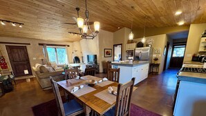 A spacious kitchen with a central island, wooden dining table with chairs, and a chandelier. - Hiking, mt biking, 44 acres to explore, 20 min outside of Santa Fe (Santa Fe)
