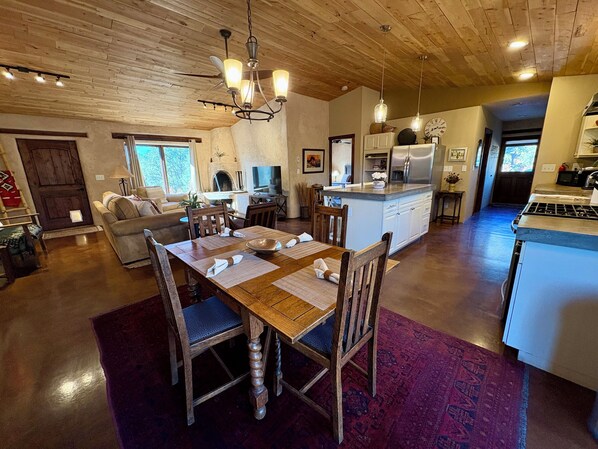 A spacious kitchen with a central island, wooden dining table with chairs, and a chandelier. - Hiking, mt biking, 44 acres to explore, 20 min outside of Santa Fe (Santa Fe)