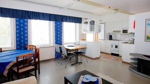 A compact living space with a dining area, kitchenette, and a small TV. - Kurimon majatalo (Suomussalmi)