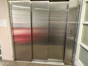 A metallic elevator with a control panel on the right side.