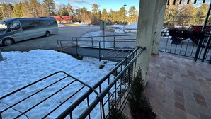 A parking area with a van, a snow-covered ground, and a building entrance with a metal railing. - Kurimon majatalo (Suomussalmi)
